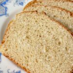 Thick slices of homemade white sandwich bread stacked on a patterned plate, perfect for everyday sandwiches and toast.