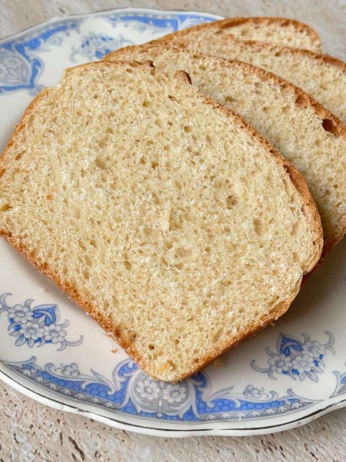 Slices of homemade white sandwich bread with a soft, even crumb and lightly golden crust, served on a vintage blue and white plate.