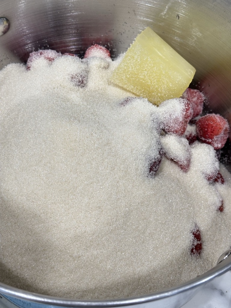 Fresh strawberries covered with sugar and lemon juice in a saucepan, the first step in making small batch strawberry jam without pectin using simple, old-fashioned ingredients.