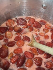 Fresh strawberries simmering with sugar and lemon juice as the mixture cooks down for a small batch strawberry jam with no commercial pectin.