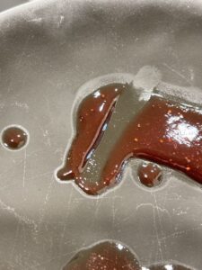 A spoonful of strawberry jam on a plate showing the gel test, a traditional way to check if small batch strawberry jam without pectin has set properly.