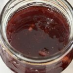 Close-up of freshly made small batch strawberry jam with no pectin, showing a glossy texture and rich strawberry colour.