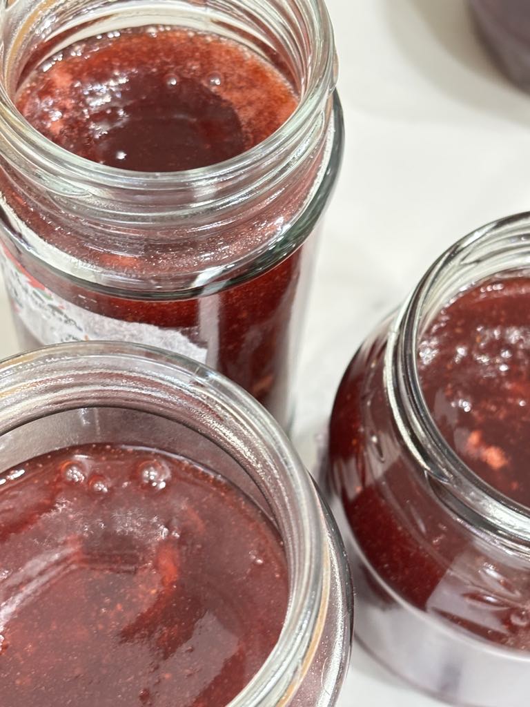 Freshly poured strawberry jam without pectin cooling in clean jars, showing the natural set achieved with lemon juice and sugar.