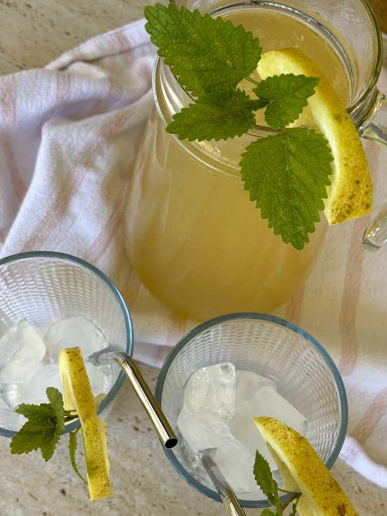 Traditional old-fashioned lemonade recipe cooling in a glass pitcher in a cozy rustic kitchen setting.