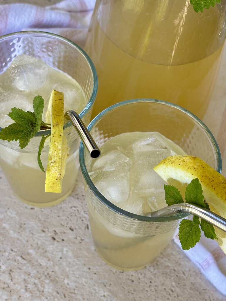 Glasses of old-fashioned lemonade recipe served with ice and lemon wedges, perfect for summer family gatherings.